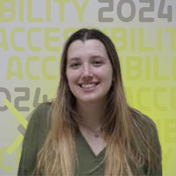 Headshot of Allie  smiling in a green sweater in a classroom setting