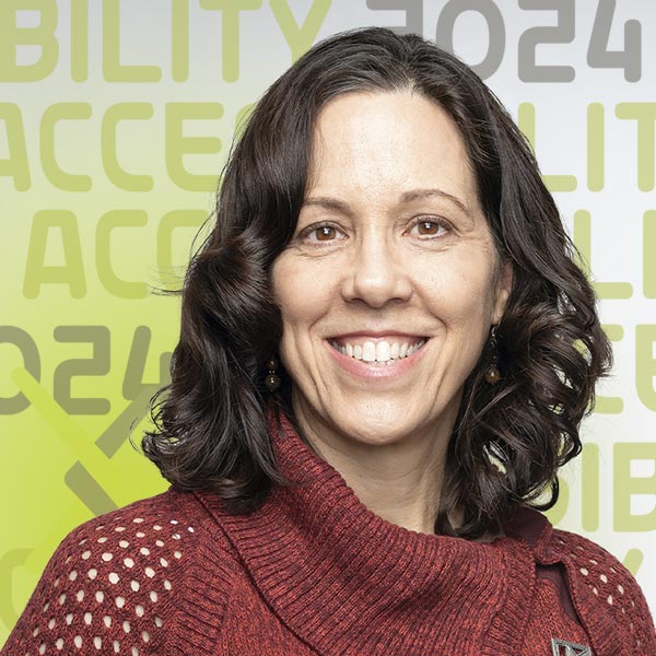 Headshot of Kate in a red sweater against a grey background