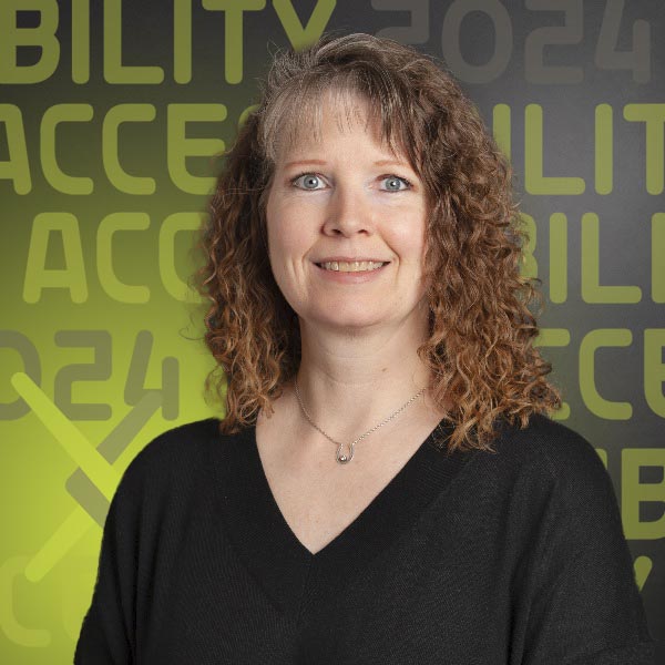 Headshot of Liz wearing a black shirt against a dark grey background