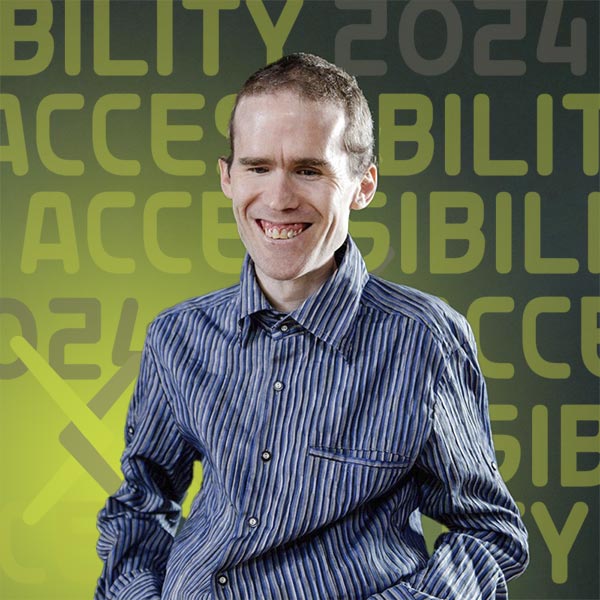 Headshot of Michael wearing a blue striped shirt standing against a dark background